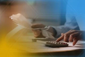 Pessoa manuseando papéis e calculadora, ilustrando a tributação para concreteiras e cálculos fiscais